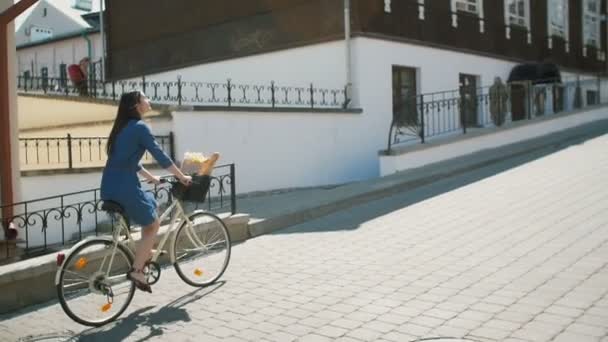 Счастливая девушка в платье, катающаяся по городу на велосипеде, медленно мчащаяся, сбитая с ног — стоковое видео