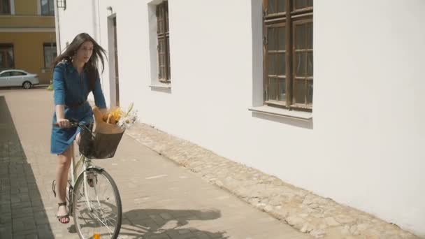 快乐美丽的黑发女孩骑着自行车在街转角在夏天，慢莫，稳定拍摄 — 图库视频影像