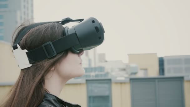 Brunette vrouw meisje met wuivende haren maakt gebruik van een virtual reality bril op het dak. 4k — Stockvideo