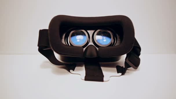 Манские руки берут очки виртуальной реальности для смартфона и носят их, смартфон работает, белый фон — стоковое видео