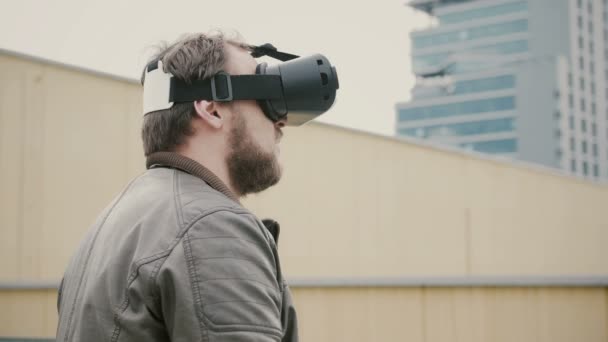 Barbudo atractivo hombre utiliza gafas de realidad virtual en el techo. 4k — Vídeo de stock