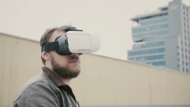 Vousatý atraktivní muž používá virtuální realitu brýlemi na střeše. 4k — Stock video