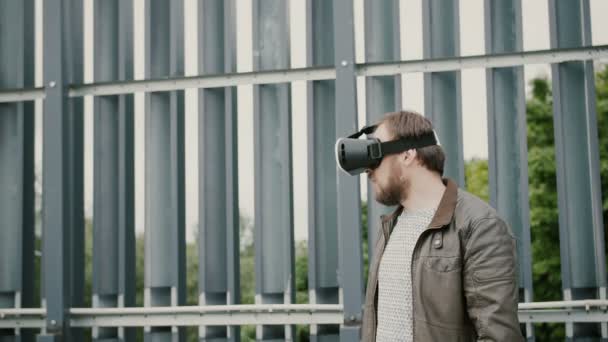Barbudo atractivo hombre utiliza gafas de realidad virtual en el espacio urbano. 4k — Vídeo de stock