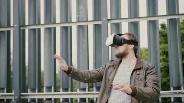 Barbudo atractivo hombre utiliza gafas de realidad virtual en el espacio urbano. 4k — Vídeos de Stock