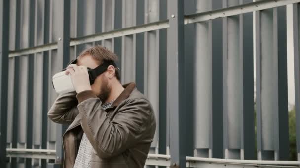 Barbudo atractivo hombre utiliza gafas de realidad virtual en el espacio urbano. 4k — Vídeos de Stock