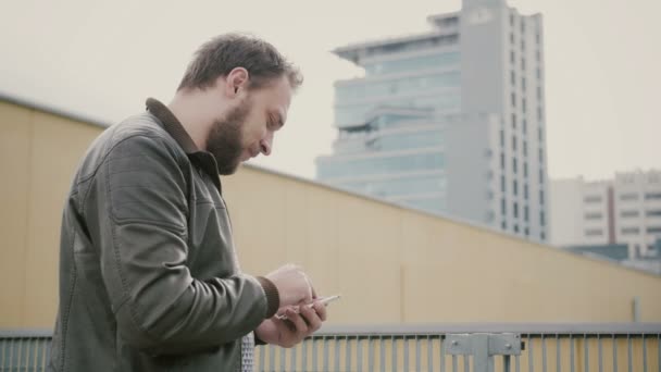 Homem usando seu smartphone em pé no telhado, em seguida, se afasta. mãos fechadas. 4k — Vídeo de Stock