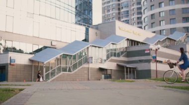 Şehirde yaz, yavaş mo bina yakınındaki Bisiklete binme uzun siyah saçlı elbiseli bir kız yan görünüm