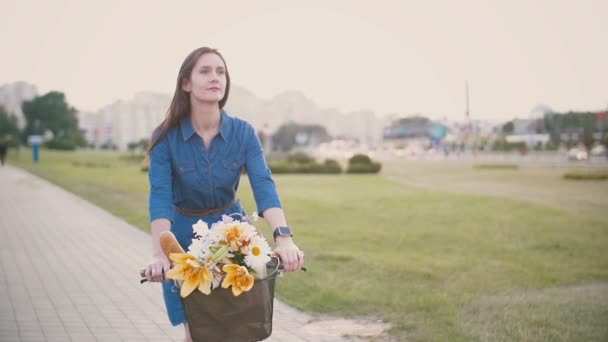 Счастливая улыбчивая девушка в платье, катающаяся по городу на велосипеде, медленно мчащаяся, сбитая с ног — стоковое видео