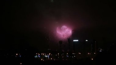 Binalar gece üzerinde yeşil, kırmızı, pembe, beyaz havai fişekler. Tatil şehir.