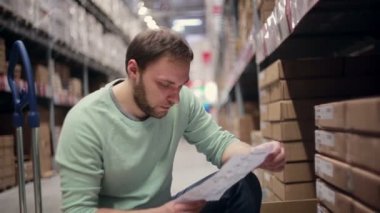 Mavi süveterli sakallı bir adam depodaki listesini kontrol etti.