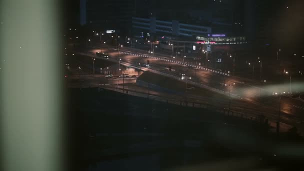 A road with cars at night in the city. A view from the window of a descending elevator. — Stock Video