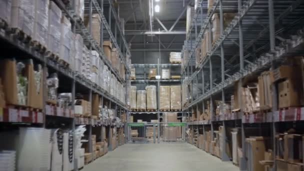Camera moves between palettes with cardboard boxes and different materials in a storage warehouse — Stock Video
