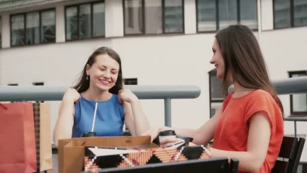 Две красивые женщины пьют кофе в кафе и разговаривают после шоппинга. 4k — стоковое видео