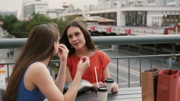 Due belle donne che bevono caffè comunicano in un caffè, parlando dopo lo shopping. 4k — Video Stock