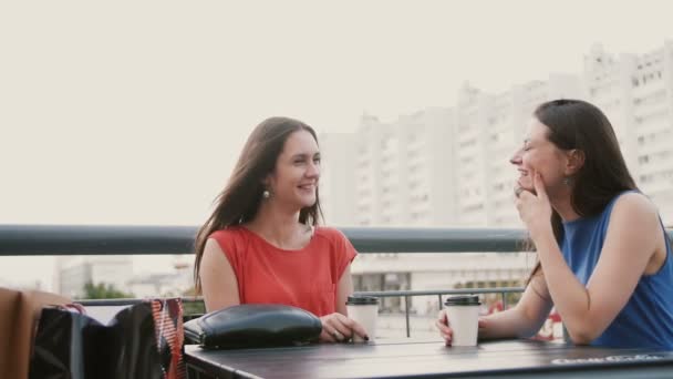 İki çekici esmer kadın en iyi arkadaş kafede kahve içme ve alışverişten sonra konuşurken. 4k — Stok video