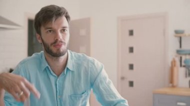Young man in a blue shirt is having a conversation in the kitchen. Slow motion