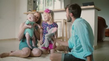 Young father is playing with his little daughter and baby son, while his wife is holding the baby. Slow motion
