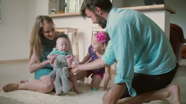 Jovem família bonita está brincando com o bebê mais novo filho no chão da cozinha. Movimento lento — Vídeo de Stock