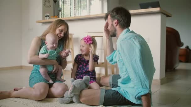 若い家族がキッチンの床に座ってキスをしています。スローモ — ストック動画