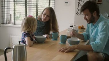 Anne mutfak masasında kocası ile konuşurken kızına gülümsüyor. Yavaş mo, Steadicam atış