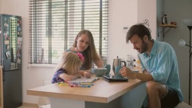 Aile yemeği sırasında baba onun ipad üzerinde çalışıyor ve bir şey bulur, eşi ona gülüyor. Yavaş mo