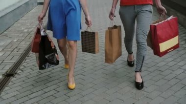 bacaklar ince genç kızlar alışveriş çantaları ile mağaza geçmiş sokakta yürürken, yavaş mo stedicam atış