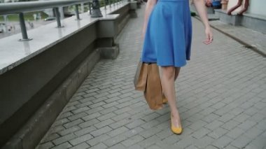 bacaklar ince genç kadın, alışveriş çantaları ile mağaza geçmiş sokakta aşağı şehirde yürüyüş, yavaş mo, stedicam vurdu