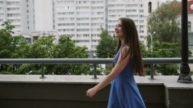 Wind blows long dark hair happy beautiful young woman walking down the street, back view, slow mo stedicam shot