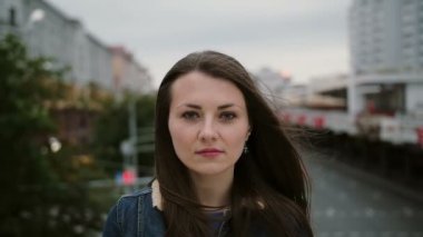 ciddi güzel kız köprüde duran, kameraya bakar, daha gülümsemeye başladı. Rüzgar saçlarını esdiriyor. yavaş çekim
