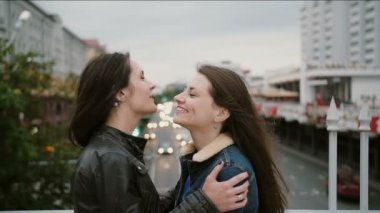 İki güzel kız en iyi arkadaş şehir köprüsünde bir araya geldi, sarılma, öpüşme, konuşma, gülümseyerek, gülüyor. yavaş mo