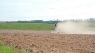 Bir tarlayı bir tarım traktör. Tepeler ve arka plan, bir orman. Her yerde toz toprak