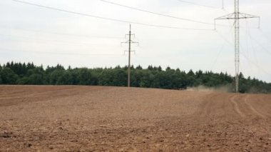 Bir tarlayı bir tarım traktör uzaktan görünür, görünür hale gelir, kamerayı taşır.