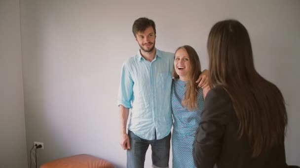 Eine junge schöne Frau und ihr Mann lachen, während sie einer Frau im schwarzen Blazer zuhören. Zeitlupe — Stockvideo