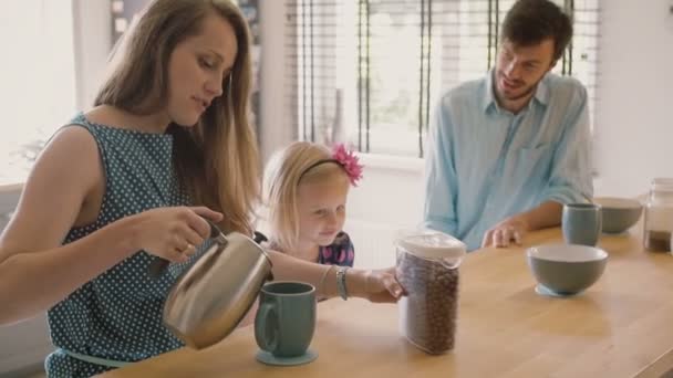 Mutlu genç aile: anne, baba ve kızı mutfak masasında kahvaltı yapıyor. Yavaş çekim — Stok video