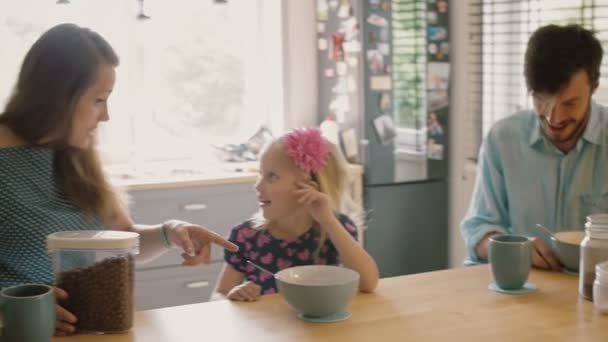 Young couple feeding their cute blond daughter breakfast in the morning. Slow motion, Steadicam shot — Stock videók