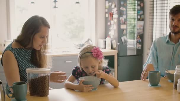 Young couple feeding their cute blond daughter breakfast in the morning. Slow motion, Steadicam shot — Stock videók