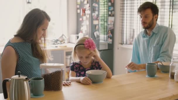 Roztomilá blonďatá dcera si něco pošeptá v matkách u snídaně. Zpomalený pohyb, střela Steadicam — Stock video