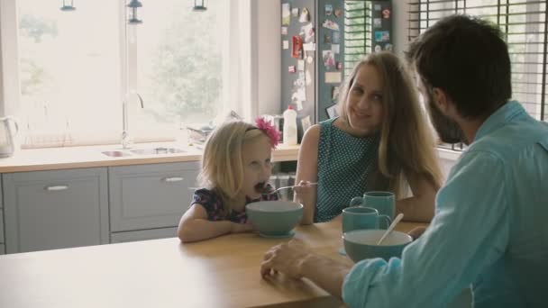 El marido está hablando con su esposa sonriente mientras su hija está desayunando. Movimiento lento — Vídeo de stock