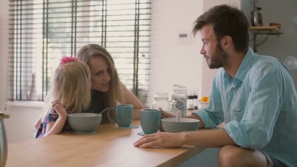 Una linda hijita está susurrando algo al oído de su madre durante el desayuno familiar. Lento mo — Vídeos de Stock