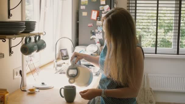 Jeune mère heureuse versant de l'eau chaude dans la tasse pour faire une tasse de thé. Slow mo, Steadicam shot — Video