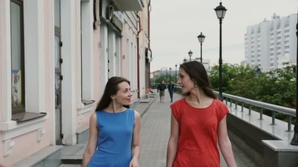 Bonnes jeunes filles amies marchant après avoir fait du shopping avec des achats en sacs, parlant et riant. ralenti mo stedicam shot — Video