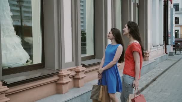 Chicas jóvenes amigos de pie cerca de escaparate con vestidos de novia y discutir. lento mo — Vídeos de Stock