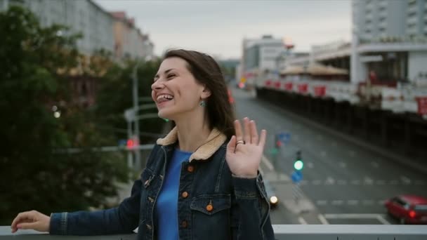 Vrolijk, vrolijk, glimlachend meisje dat op de brug staat, veel plezier, poseren kijkt naar de camera. Slow Motion — Stockvideo