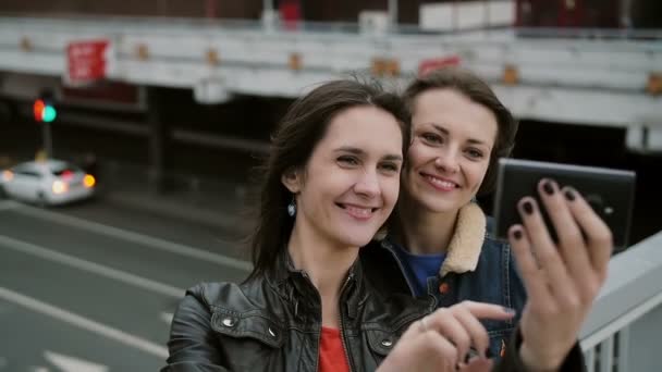 İki kız en iyi arkadaş selfie çekiyor, şehir köprüsünde duruyor, konuşuyor, gülümsüyor, gülüyor. yavaş mo. — Stok video