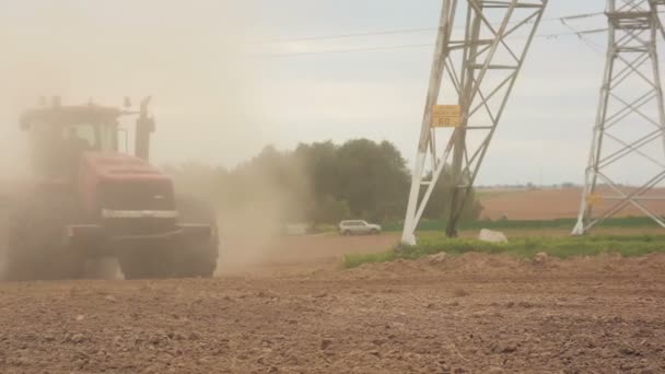 An agricultural tractor plowing a field before sowing. Hills and a forest at the background. Soil dust all over — Stock Video