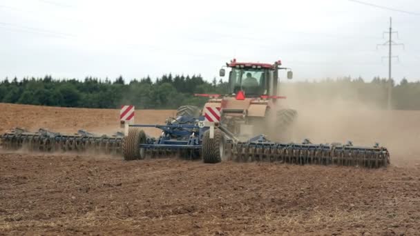 Egy mezőgazdasági traktor szántás mező áthelyezése a kamera. Talaj por. — Stock videók