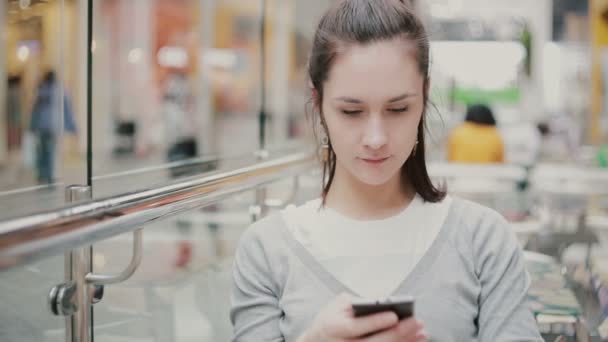 Una giovane donna in maglione grigio con il suo smartphone . — Video Stock