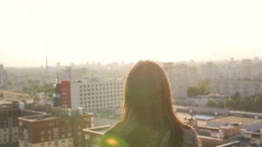 young woman jumping standing on the roof at sunset. slow mo