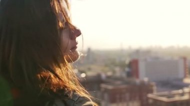çatıda duran bir kızın yakın portresi ve şehrin manzarasının keyfini çıkarın. Yavaş çekim