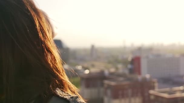 Primer plano retrato de una chica de pie en el techo chica endereza su cabello, mirando a la ciudad. Movimiento lento — Vídeos de Stock